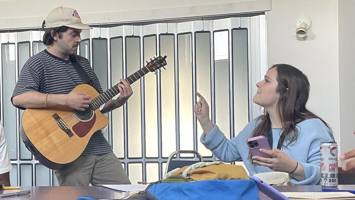 Une personne joue de la guitare et une autre la regarde.