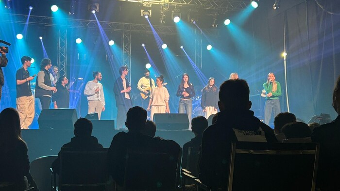 Des spectateurs observent des artistes sur scène. 