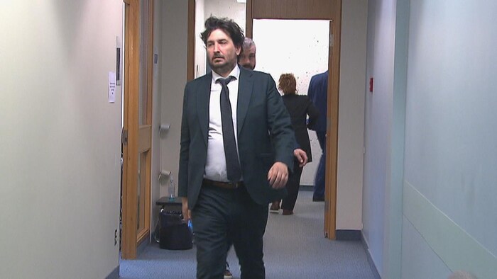 Un homme qui marche dans un corridor d'un palais de justice.