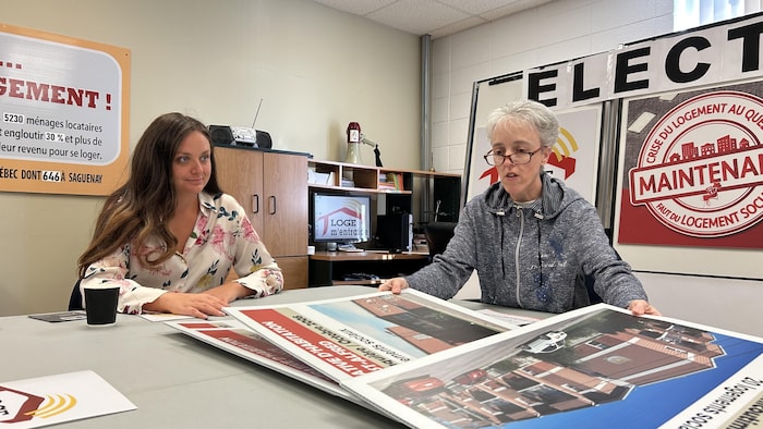 Deux femmes examinent des pancartes sur une table.