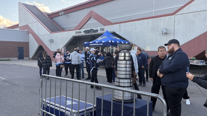 Une vingtaine de personnes sont rassemblées sur le stationnement, dont certaines aux couleurs des Saguenéens.