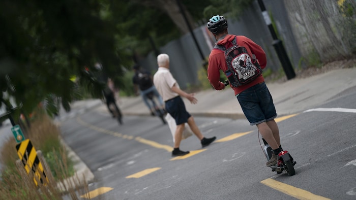 Une homme sur une trottinette électrique et un piéton.