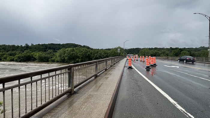 Des cônes bloquent une voie sur un pont.