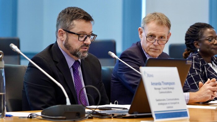 Troy Charter parle devant les médias et des conseillers municipaux.