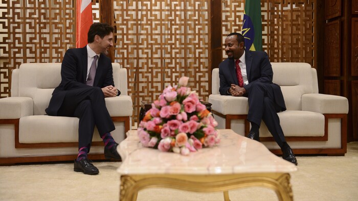 Justin Trudeau et Abiy Ahmed assis côte à côte, se parlant.