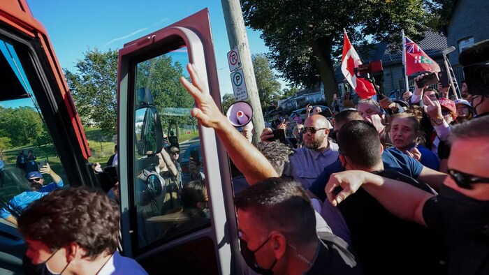 RCMP officers put their hands up to protect Justin Trudeau as protesters shout and throw gravel at a campaign stop during last year's federal election in London, Ont., on Sept. 6, 2021. (Nathan Denette/The Canadian Press)