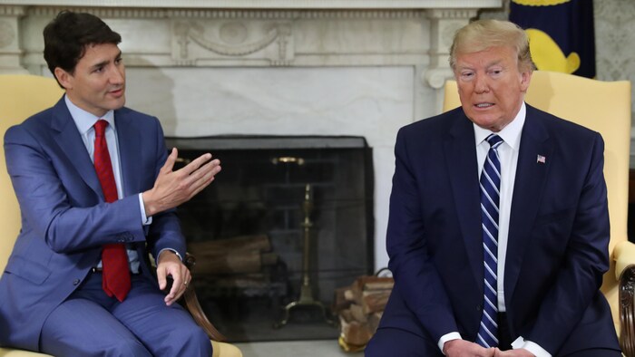 Justin Trudeau fait un geste de la main pendant que Donald Trump écoute. 