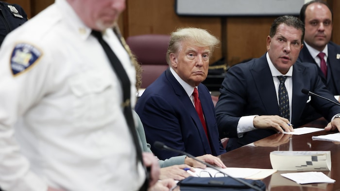 Donald Trump est assis dans une salle d'audience avec ses avocats à New York. 