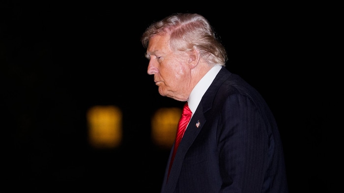 Donald Trump, de profil, marche en regardant vers le sol.