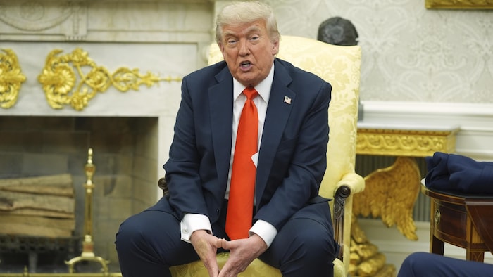 Donald Trump, assis au bureau ovale, parle.