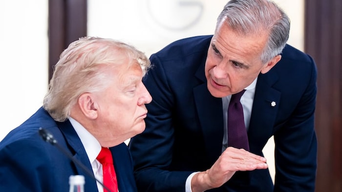 Debout à ses côtés, Mark Carney parle à Donald Trump qui est assis.