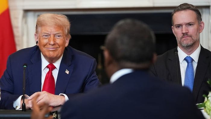 Jamieson Greer assis à la droite de Donald Trump, devant un autre homme.