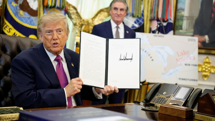 Donald Trump tient fièrement le document de son décret dans le bureau ovale.