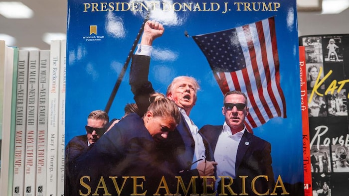 Le livre, qui montre Donald Trump, ensanglanté, lever le bras devant un drapeau américain, est sur une étagère.