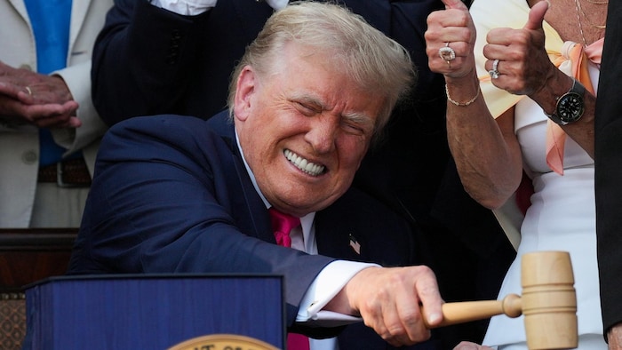 Un homme sourit et tient un marteau dans sa main.