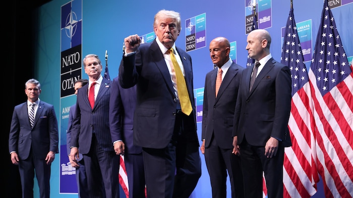 Donald Trump marche sur une scène en levant faiblement le poing dans les airs.