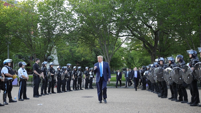 Donald Trump marche entre deux rangées de policiers.