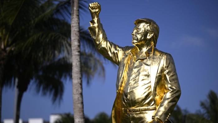 À la tombée du jour, une statue en or montre Donald Trump, le poing levé.