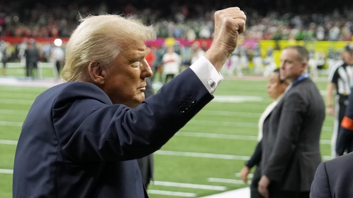 Donald Trump, poing en l'air, sur un terrain de football.