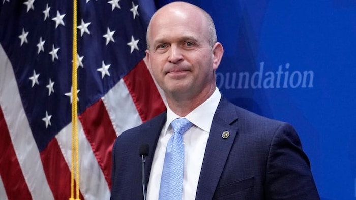 Un portrait de M. Roberts devant un drapeau américain.