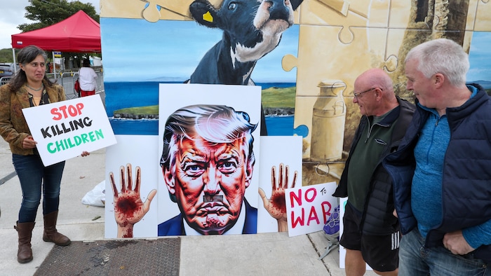 Des manifestants brandissent des pancartes pour protester contre la visite du président américain Donald Trump, à Doonbeg, dans l'ouest de l'Irlande, le 12 septembre 2026, où le président américain assiste au tournoi de golf de l'Open d'Irlande sur son parcours de golf situé à proximité.