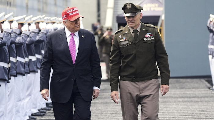 Un homme en costume et portant une casquette MAGA marche avec un homme habillé en uniforme militaire à une cérémonie de collation des grades de l'Académie militaire de West Point.