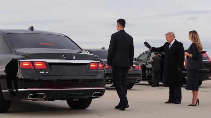Un homme, accompagné de sa femme, salut quelqu'un dans une limousine qui démarre.