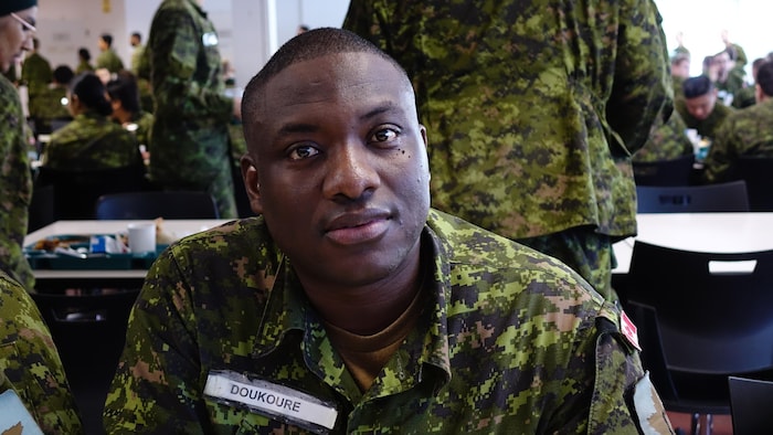Un homme noir en uniforme assis à la cafétéria.