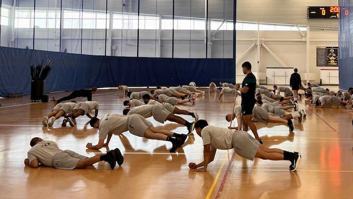 Des recrues à l'entraînement dans un gymnase font la planche.