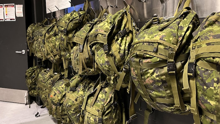 Des sacs à dos de militaires suspendus à des crochets.