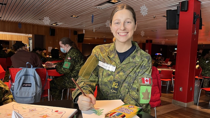 Jeune femme en habit de militaire et crayon à la main.