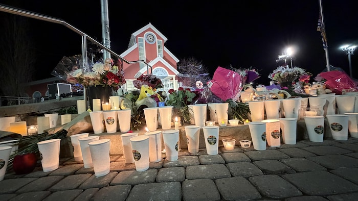Des chandelles brulent illuminant des fleurs et des peluches forment un mémorial spontané sur les marches menant à l'hôtel de ville de Tumbler Ridge le surlendemain de la tuerie.