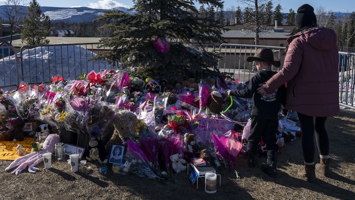 Une mère et son fils se sont rendus, le 14 février, devant un mémorial pour rendre hommage aux victimes de la tuerie de Tumbler Ridge, en Colombie-Britannique.