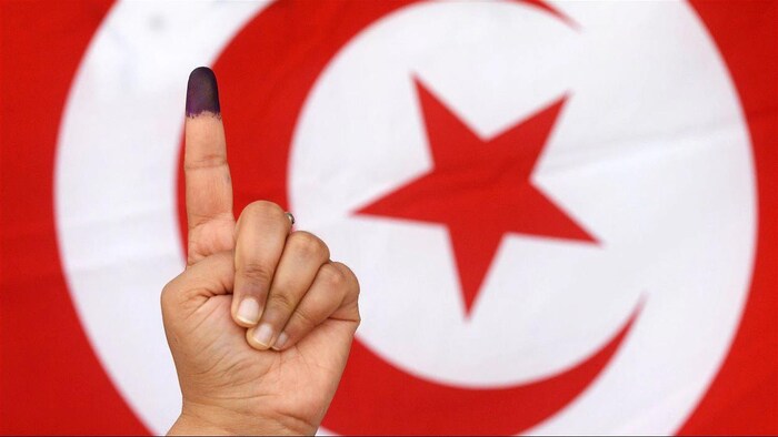 أصبع ملطخ بالحبر امام علم تونس.