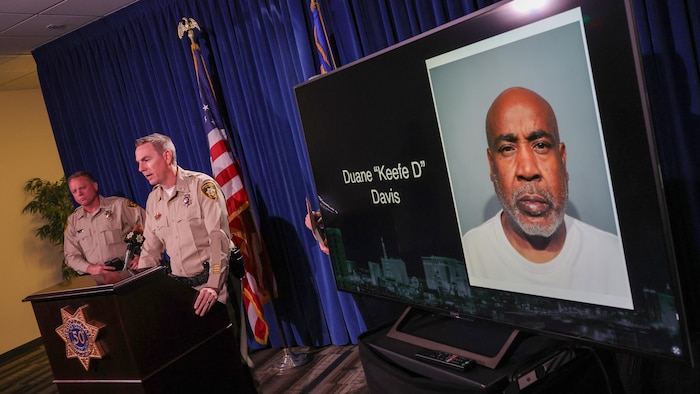 Une photo de Duane «Keefe D» Davis est affichée sur un écran pendant que le shérif du comté de Clark, Kevin McMahill (à gauche), et le lieutenant Jason Johansson (à droite), du Service de police métropolitaine de Las Vegas, parlent lors d'une conférence de presse.