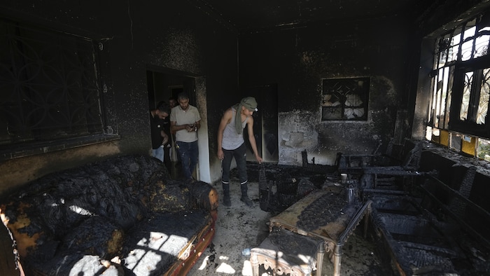 Des Palestiniens inspectent l'intérieur d'une maison incendiée. 