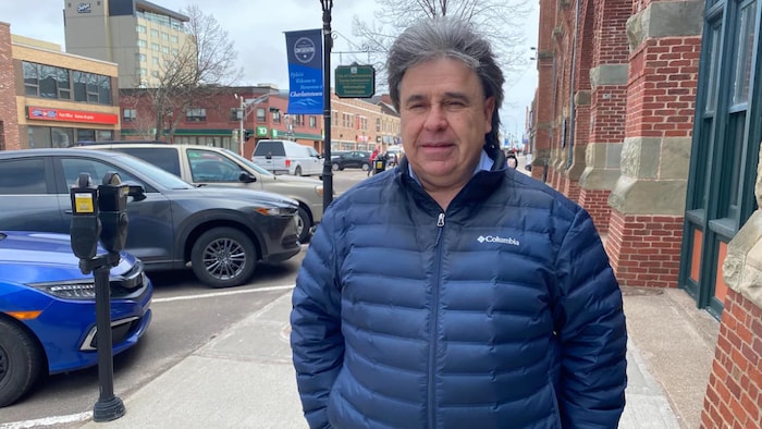 Mitchell Tweel debout sur un trottoir du centre-ville, chevelure au vent.