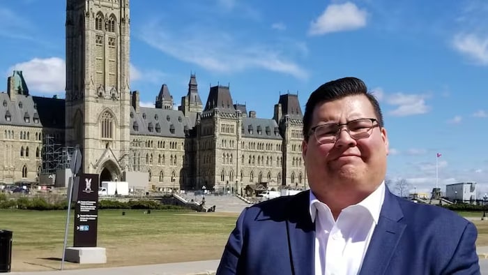 Tyson Wesley, en lunettes, se tient debout devant un bâtiment.