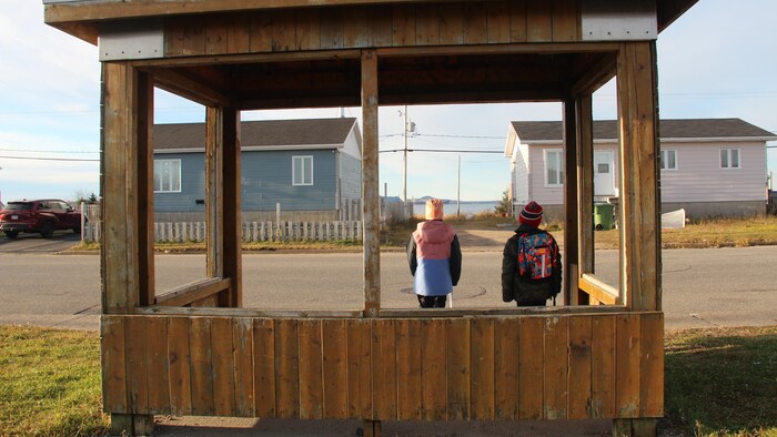 Deux enfants attendent dans un abribus.