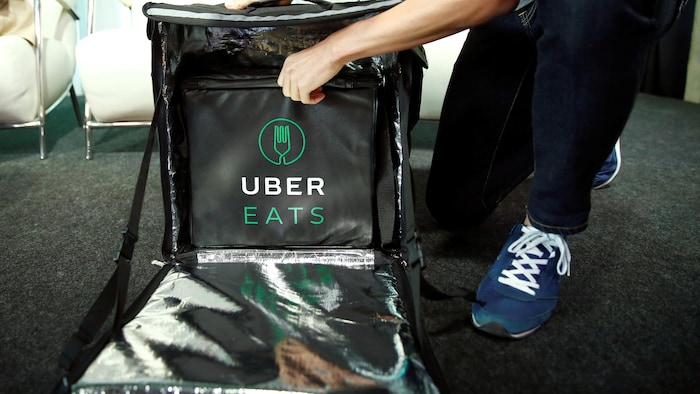 Un chauffeur d'Uber Eats se prépare à livrer un repas, en ouvrant son sac de livraison.