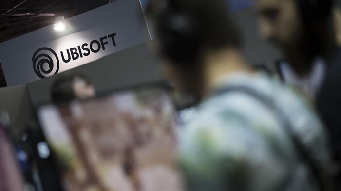 Le logo et le mot Ubisoft apparaissent au-dessus d'une portion floue de la photo où l'on distingue un homme de profil qui semble avoir un casque d'écoute sur la tête.