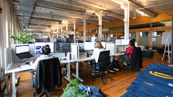 Des personnes travaillent à l'ordinateur dans un espace de bureaux ouvert. 