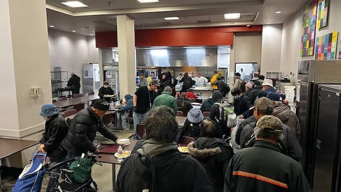 Un groupe de personnes qui attendent en ligne pour être servie de la nourriture. 