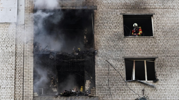 Des pompiers à l’œuvre dans un immeuble résidentiel touché par une frappe d'un drone russe à Kiev le 25 septembre 2026.