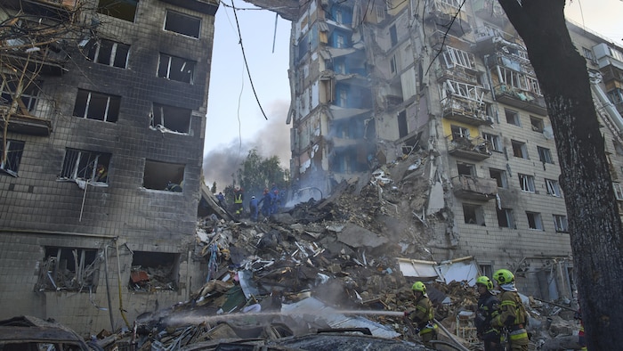 Des pompiers arrosent les décombres d'un immeuble résidentiel à Kiev.