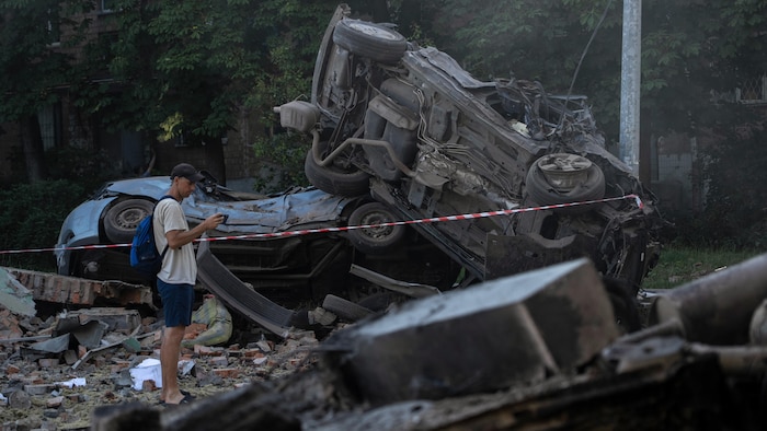 Un homme regarde les débris de voitures après les frappes massives de drones et de missiles russes sur la capitale ukrainienne, Kiev, le 4 juillet 2025.