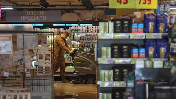 Un travailleur lave le plancher d'un supermarché.