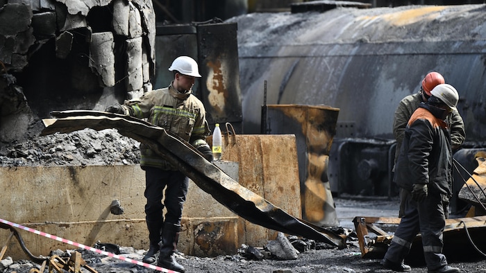 Des ouvriers nettoient les débris dans un hall de turbine rempli d'équipements brûlés dans une centrale électrique du fournisseur d'énergie DTEK, détruite après une attaque, dans un lieu non divulgué en Ukraine.