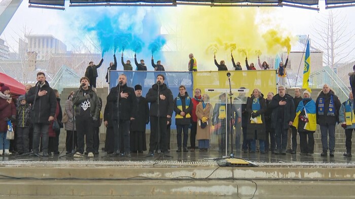 Des chanteurs sur une scène et de la fumée bleu et jaune, aux couleurs du drapeau ukrainien, derrière eux.