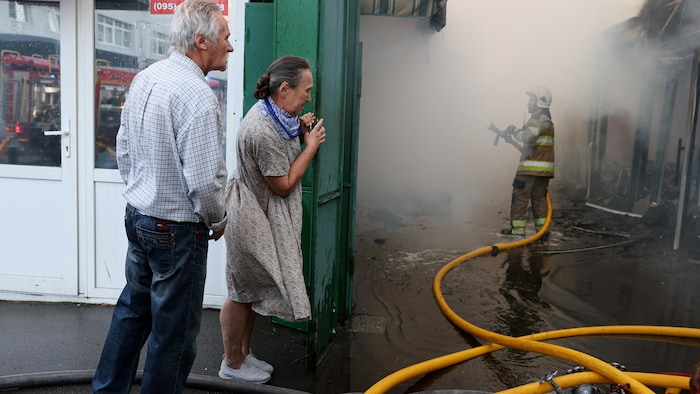 Deux personnes regardent un pompier entouré de fumée.